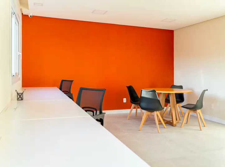 Sala de coworking com mesas de trabalho e área de reunião