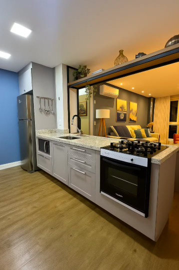 Cozinha com fogão cooktop, forno e bancada em granito